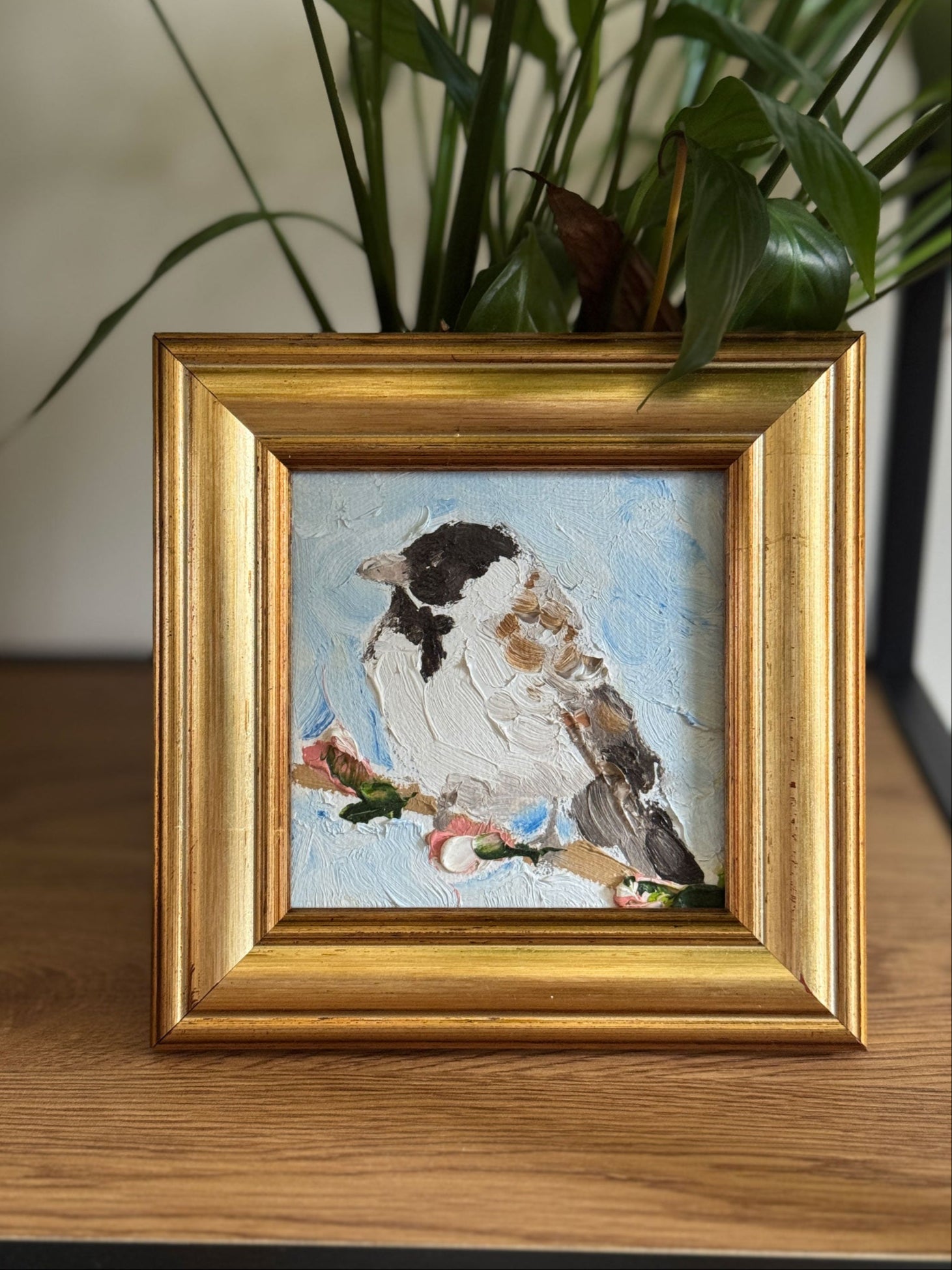 Framed artwork of a Reed Bunting bird on a wooden surface with plants in the background created by Mark Gilmour Northern Ireland Artist